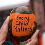 Every Child Matters written on an orange shirt painted on a rock